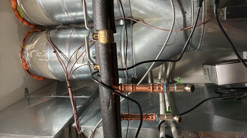 Replaced two circulator pumps in the hydronic heating system and installed new service ports to facilitate future maintenance access. Replaced the air separator head assembly and reconnected all copper piping with proper fittings and support brackets. The installation includes a manifold distribution system with zone control valves, integrated electrical controls, and insulated piping connections to the existing ductwork infrastructure.