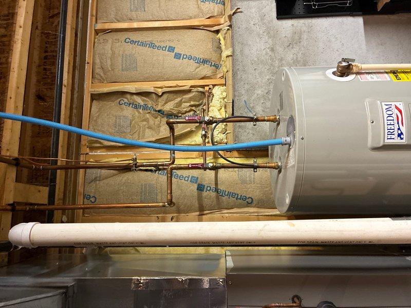 Completed on-site assessment of existing 20+ year old Freedom brand water heater located in basement utility area. Unit currently operational but nearing end of service life. Documented existing installation including copper supply lines with brass fittings, blue flexible water line connections, PVC drain line, and metal condensate pan positioned beneath unit. Water heater installed against framed wall with fiberglass insulation. Inspected supply line routing from basement through upper floor space, noting copper piping with shutoff valves and directional fittings. Provided comprehensive estimate for water heater replacement. Additionally assessed property for whole-house water filtration system installation and provided separate estimate for filtration equipment and installation.
