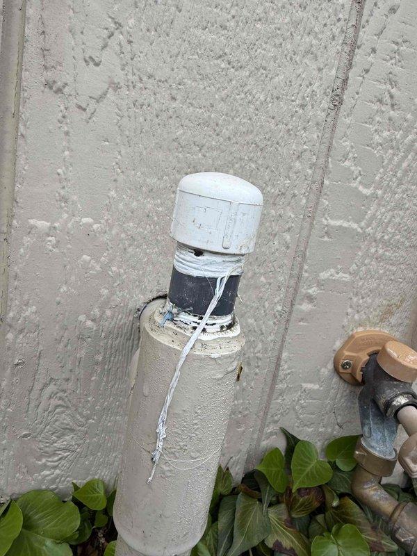 Responded to reported water leak from PVC pipe cap on exterior plumbing system. Upon inspection, identified leaking cap fitting at top of vertical drainage pipe mounted on exterior wall. Repaired compromised connection by securing brass compression fittings and replacing worn gasket components. Verified proper seal and confirmed leak was eliminated upon completion of repairs.