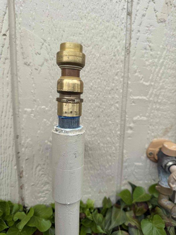 Responded to reported water leak from PVC pipe cap on exterior plumbing system. Upon inspection, identified leaking cap fitting at top of vertical drainage pipe mounted on exterior wall. Repaired compromised connection by securing brass compression fittings and replacing worn gasket components. Verified proper seal and confirmed leak was eliminated upon completion of repairs.