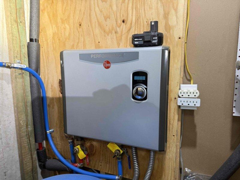 Conducted on-site evaluation for installation of Rheem Performance tankless gas water heater and associated gas line extension. Assessed existing utility room infrastructure, including current gas supply configuration, electrical requirements, and plumbing connections. Evaluated placement location on plywood wall with adequate clearance for proper ventilation and code compliance. Documented existing installation showing tankless unit with digital display controls, gas shut-off valves with yellow handles, blue PEX water supply lines, and flexible gas connector. Reviewed electrical outlet accessibility and determined requirements for additional gas line routing from existing supply to support new water heater demand. Provided comprehensive estimate covering materials and labor for gas line installation, water heater mounting, venting system, condensate drainage, and all necessary connections to integrate unit into residential plumbing system.