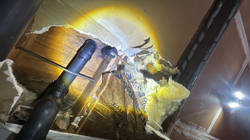 Responded to leaking shower faucet in second floor bathroom. Accessed plumbing lines through ceiling cavity to diagnose and repair the water supply issue. Work required opening drywall access panel, exposing PVC supply lines and surrounding insulation to locate source of leak and complete necessary repairs to restore proper faucet operation.