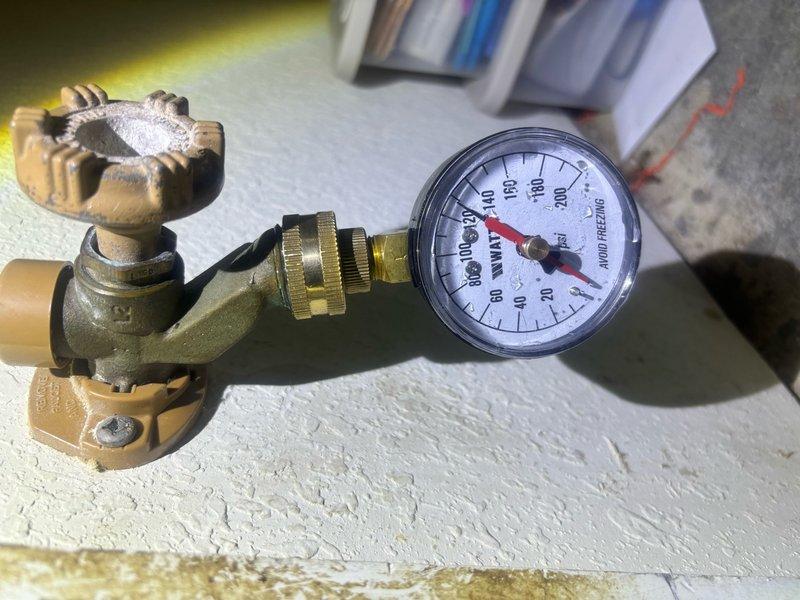 Responded to service call for residential water heater experiencing temperature fluctuations and complete loss of hot water. Upon arrival, inspected tanked water heater unit located in garage. Found system pressure gauge reading near zero, indicating potential pressure relief valve failure or significant loss of system pressure. Evaluated temperature and pressure relief valve assembly, brass valve connections, and associated plumbing infrastructure including copper supply lines with foam insulation and PVC drainage piping. Diagnosed faulty temperature control mechanism causing initial scalding condition followed by complete system shutdown. Performed necessary repairs to restore proper water heating function and system pressure to safe operating levels throughout the home.