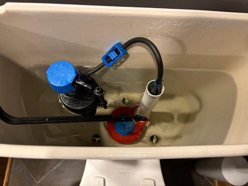 Completed routine plumbing maintenance inspection of one unit. Verified backflow preventer pressure gauge reading at approximately 140 psi within normal operating parameters. Inspected toilet tank internal components including flush valve assembly with red rubber flapper seal and fill valve mechanism with refill tube connection, confirming all components properly installed and functional.