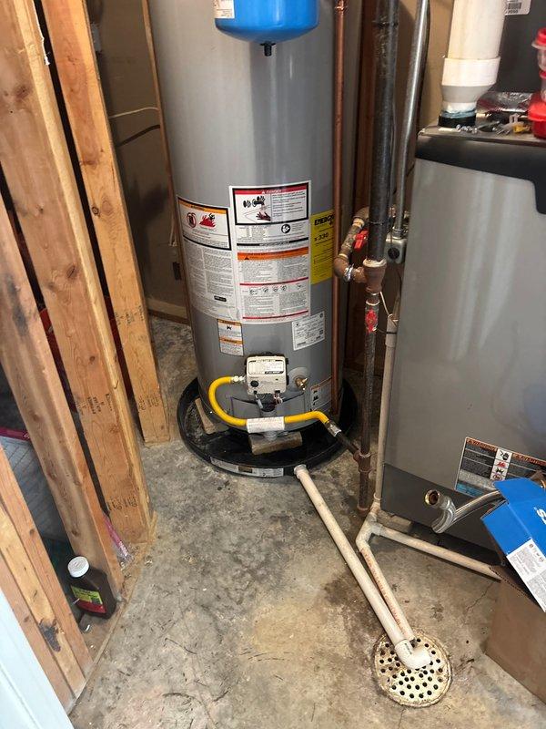 Installed 50-gallon gas water heater with thermal expansion tank mounted at top of unit. Replaced and installed 3/4-inch pressure reducing valve and repaired approximately 3 feet of water supply line. Connected yellow flexible gas line to unit base with shutoff valve, ran copper piping with brass fittings for hot and cold water connections, and installed white PVC drain line at floor level. All plumbing connections secured and tested for proper operation and pressure regulation.