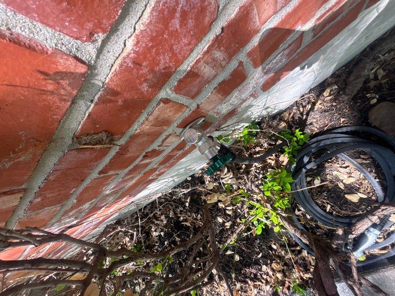 Responded to service call for gas leak detection and pressure testing with gas supply in off position. Conducted thorough inspection of property exterior, focusing on areas near foundation and planting beds adjacent to brick wall structure. Documented conditions of outdoor plumbing fixtures and surrounding areas with photographic evidence. Additionally identified and documented water leak at exterior faucet requiring repair. Completed visual inspection of accessible gas lines and plumbing components in affected areas.