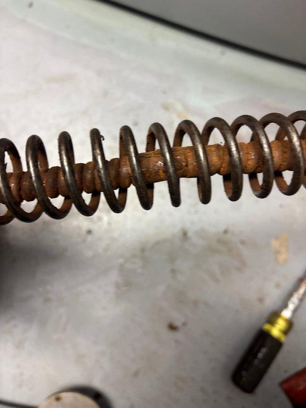 Responded to clogged floor drain in basement. Upon inspection, found heavy rust staining around drain opening with standing water present. Deployed drain snake through the opening to clear blockage. Successfully removed corroded metal spring coil that had become lodged in the drain line, which was the source of the obstruction. Drain now flowing properly with blockage completely cleared.