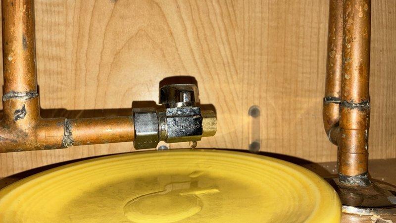 Responded to callback for supply line leak that persisted after previous day's repair. Upon inspection, identified continued leak at brass valve connection on copper supply line above water heater drip pan. Tightened compression fittings at valve assembly, verified all connections were secure, and confirmed leak was resolved. Tested system under full pressure with no further seepage detected.