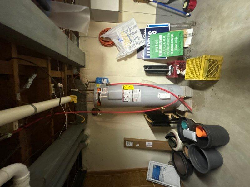 Responded to service call for non-operational water heater in basement. Upon inspection, diagnosed State brand tanked water heater with associated plumbing configuration including copper piping, expansion tank, and gas supply line. Evaluated system components including the blue expansion tank mounted horizontally on the piping assembly and verified proper connections throughout the water heater installation. Documented existing equipment setup and provided assessment of necessary repairs to restore hot water functionality.