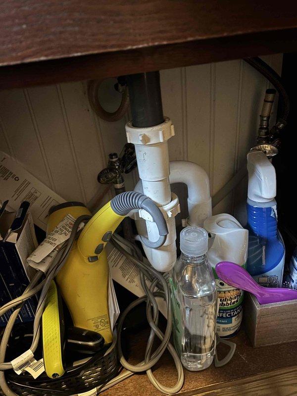 Responded to reported water leak in upstairs bathroom originating from either sink or toilet. Upon inspection, accessed under-sink cabinet area and examined plumbing configuration including PVC P-trap assembly, metal tailpiece, and chrome supply lines with shut-off valves. Investigated adjacent crawl space or wall cavity where deteriorated pipe work showed significant corrosion, rust patches, and aging metal surfaces. Completed diagnostic assessment and necessary repairs to resolve the leak issue.