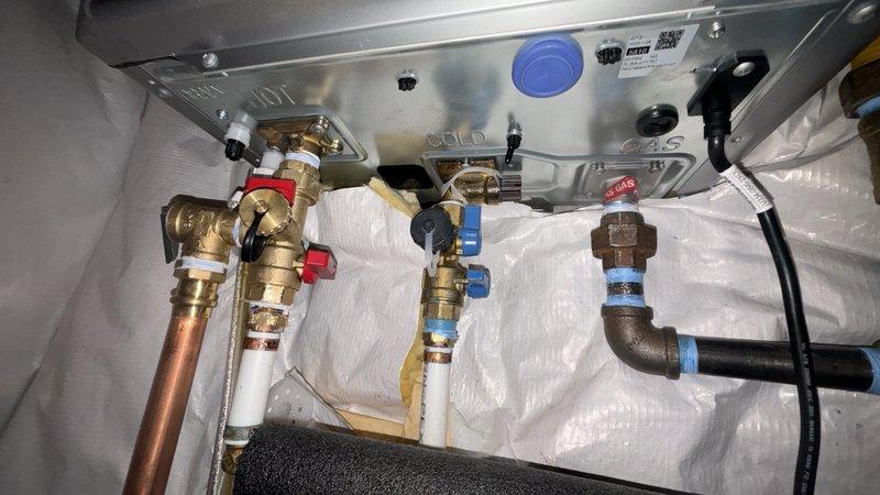 Completed warranty replacement of Rinnai tankless water heater unit per case #254181. Removed existing failed unit and installed new Rinnai tankless water heater in confined utility space, connecting all copper supply lines, brass shut-off valves, pressure relief valve, and PVC venting system. Verified all connections for proper operation and tested unit functionality upon completion.