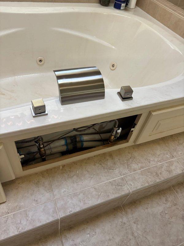 Installed customer-supplied bathtub faucet assembly with brushed metal finish, including center-mounted spout and dual control knobs. Connected supply lines to existing shut-off valves, verified proper water flow and pressure, and tested for leaks at all connection points.