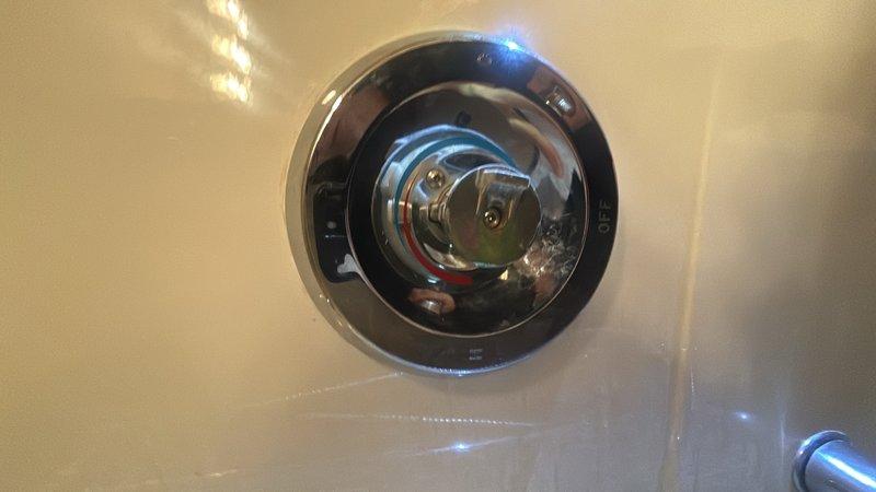 Responded to hallway shower valve malfunction where handle would not turn off water flow. Upon arrival, main water supply had already been shut off by occupant. Removed existing MOEN brand shower valve trim and cartridge assembly from white tiled shower wall. Installed replacement MOEN valve cartridge and reassembled chrome-finished circular control fixture. Tested operation to verify proper function and complete water shutoff capability. Restored main water supply and confirmed no leaks at valve assembly.