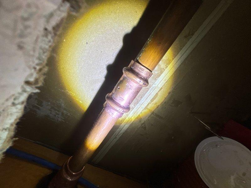 Responded to emergency call regarding water leak from broken faucet in basement wall. Upon arrival, located source of leak at corroded copper pipe connection near foundation. Assessed exterior hose bib assembly and traced supply line to compromised joint showing significant oxidation and pink discoloration indicating active corrosion failure. Replaced damaged copper pipe section and coupling, secured all connections, and pressure-tested system to verify leak elimination. Exterior spigot assembly inspected and confirmed operational with garden hose attachment functioning properly.