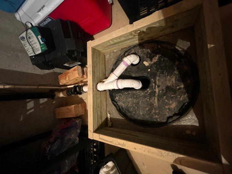 Responded to service call for sump pump malfunction in basement southeast corner of 29-year-old residence. Upon inspection, found significant sediment and debris accumulation at bottom of sump basin, with yellowish-brown material buildup affecting pump operation. Unit was approximately 1–1.5 years old and installed in cylindrical basin with dual PVC discharge lines. Removed accumulated sediment and debris from basin floor that was restricting float switch movement and potentially impacting pump performance. Inspected electrical connections, float switch assembly, and discharge piping configuration. Verified proper operation of pump motor and check valve function. Cleaned basin interior walls showing mineral deposits and staining. Tested pump cycle through multiple activations to ensure proper float engagement and discharge flow. Confirmed adequate drainage through both discharge lines and verified no blockages in piping system. System restored to full operational status.