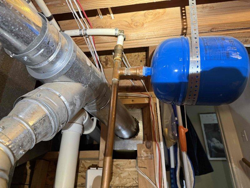 Conducted on-site evaluation of residential water heater system following customer report of corrosion concerns. Inspected water heater installation located in attic space, including associated copper supply piping, brass fittings, expansion tank, and shutoff valves. Documented existing system configuration with photographic evidence showing thermal expansion tank mounted to ceiling joists, copper water lines with visible patina, HVAC ductwork proximity, and electrical connections. Assessed condition of all visible components including pipe connections, tank mounting hardware, and surrounding mechanical systems to provide comprehensive estimate for water heater replacement options and address corrosion issues.
