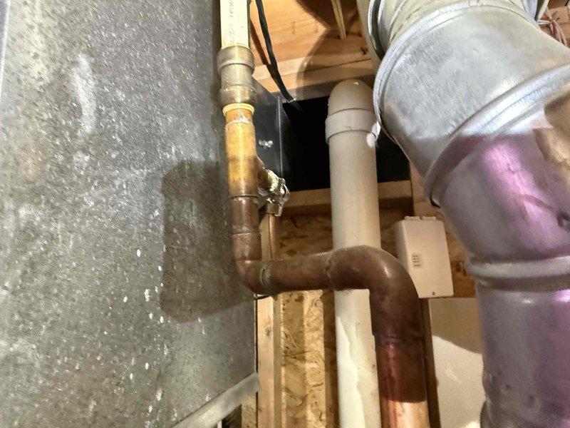 Conducted on-site evaluation of residential water heater system following customer report of corrosion concerns. Inspected water heater installation located in attic space, including associated copper supply piping, brass fittings, expansion tank, and shutoff valves. Documented existing system configuration with photographic evidence showing thermal expansion tank mounted to ceiling joists, copper water lines with visible patina, HVAC ductwork proximity, and electrical connections. Assessed condition of all visible components including pipe connections, tank mounting hardware, and surrounding mechanical systems to provide comprehensive estimate for water heater replacement options and address corrosion issues.