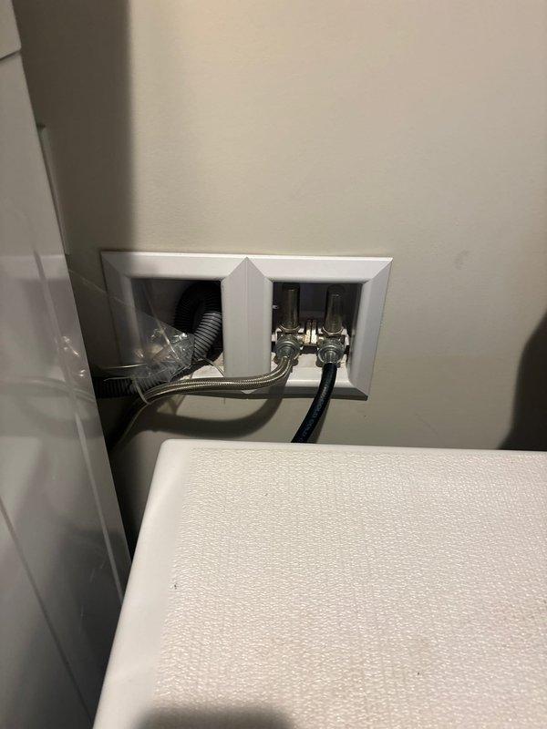 Completed utility sink installation in garage. Accessed wall cavity through drywall opening to connect supply lines and drain plumbing to existing infrastructure. Installed washer box with dual chrome water supply valves, braided stainless steel supply lines, and corrugated drain hose with appropriate fittings. All connections secured and tested for proper operation.