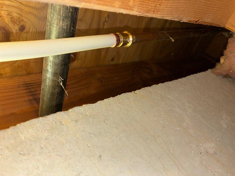 Responded to service call for exterior spigot that had blown out and was leaking back into the house when used. Accessed interior wall and attic space to locate the failed connection point where the outdoor faucet line penetrated the building envelope. Replaced damaged section of water line with new white PEX piping and brass compression fittings, properly securing the pipe through the wooden framing members. Created wall access point to reach the compromised plumbing, exposing R-13 insulation and vapor barrier to complete the repair. Tested the outdoor spigot for proper operation and verified no water was leaking back into the interior spaces.