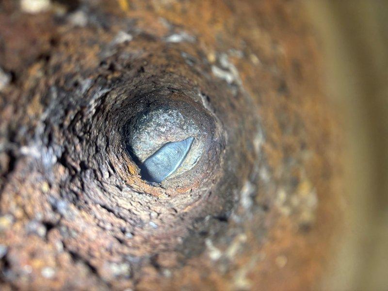 Responded to basement floor drain backflow with paper debris in 114-year-old single-family residence. Accessed main sewer line through basement cleanout and performed comprehensive video camera inspection, revealing significant corrosion and deterioration of cast iron drain piping with rust buildup and mineral deposits throughout the line. Performed mechanical cable cleaning of main drain line to remove debris obstruction and restore proper flow, clearing paper materials and accumulated sediment causing the backflow condition. Advised property owner of advanced pipe deterioration observed during inspection and recommended monitoring for potential future line replacement due to age and condition of original 1912 plumbing infrastructure.