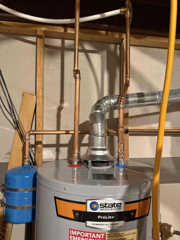Installed a 40-gallon State ProLine commercial grade gas water heater in the utility area with proper copper piping connections and brass compression fittings at the top of the unit. A blue thermal expansion tank was securely mounted to the wall framing with metal strapping and integrated into the plumbing system. Flexible corrugated stainless steel tubing (CSST) gas lines were connected with a red-handled gas shut-off valve to the black iron gas supply pipe, ensuring safe and code-compliant gas delivery to the unit.