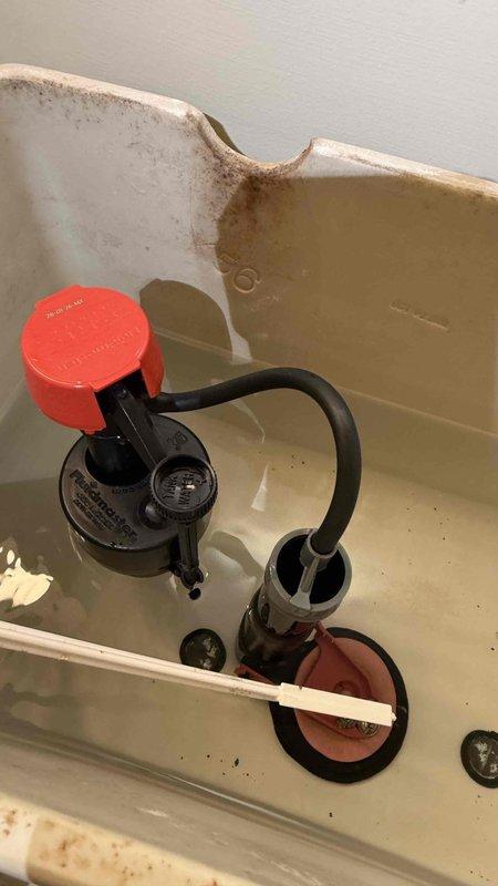 Responded to service call for constantly running toilet on main level. Upon inspection, found deteriorated red rubber flapper on flush valve mechanism causing continuous water flow into bowl. Toilet tank exhibited significant age-related staining, mineral deposits, and discoloration throughout interior surfaces. Replaced faulty flapper assembly and tested flush valve operation to ensure proper seal and water shutoff. Verified fill valve with red cap functioning correctly and adjusted water level as needed. System tested multiple times to confirm toilet no longer running and all components operating within normal parameters.
