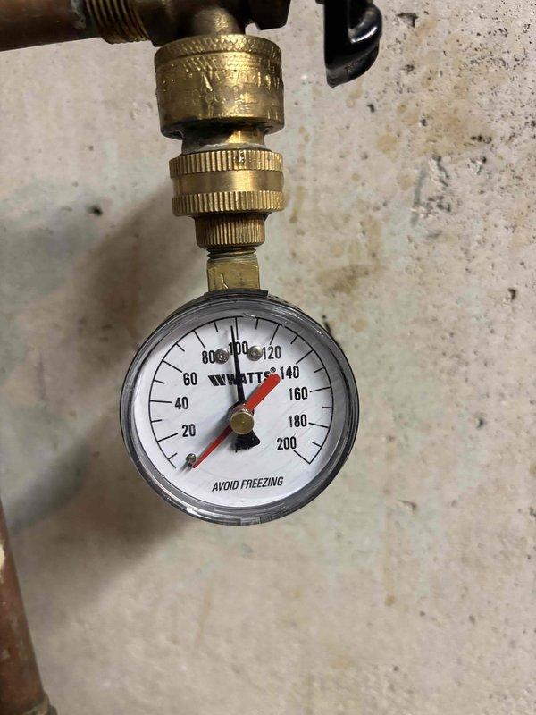 Replaced defective pressure valve regulator in basement plumbing system. Upon completion, verified proper water pressure regulation with gauge reading approximately 100 PSI and confirmed system operation within normal parameters.