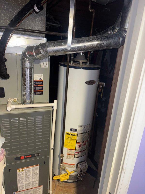 Responded to service call for water heater with pilot light that would not remain lit. Upon inspection, determined that repair was not viable and proceeded with full replacement of existing tanked water heater. Removed old 50-gallon residential water heater from utility closet adjacent to Trane furnace unit. Disconnected existing gas line, cold water supply, and hot water outlet connections. Installed new 50-gallon tanked water heater in same location. Connected gas supply piping using black iron pipe, ensuring proper threading and joint sealing. Attached copper water supply lines with appropriate brass fittings and verified all connections were secure. Installed temperature and pressure relief valve with proper discharge piping. Lit pilot light, tested burner operation, and verified proper ignition sequence. Checked all gas connections for leaks using approved detection methods. Confirmed adequate combustion air supply and proper venting. Set thermostat to manufacturer recommended tem