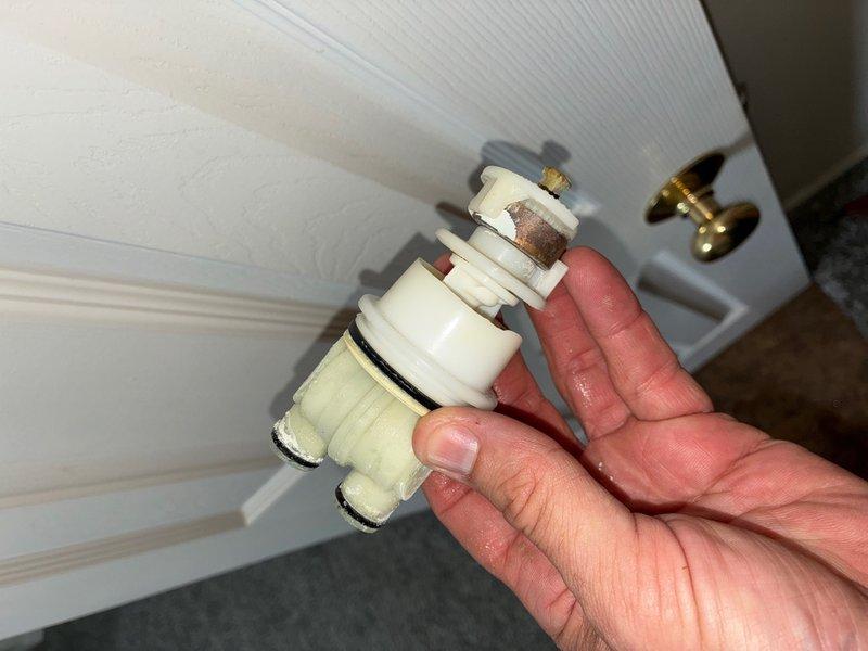 Responded to a leak complaint at a shower valve causing water intrusion through the floor to the garage below. Performed diagnostic inspection and removed the dual-stem shower cartridge assembly, which revealed significant corrosion and mineral deposits on the metal valve stems and brass threading. Documented the failed cartridge condition and provided rough estimate for cartridge replacement to resolve the active leak.
