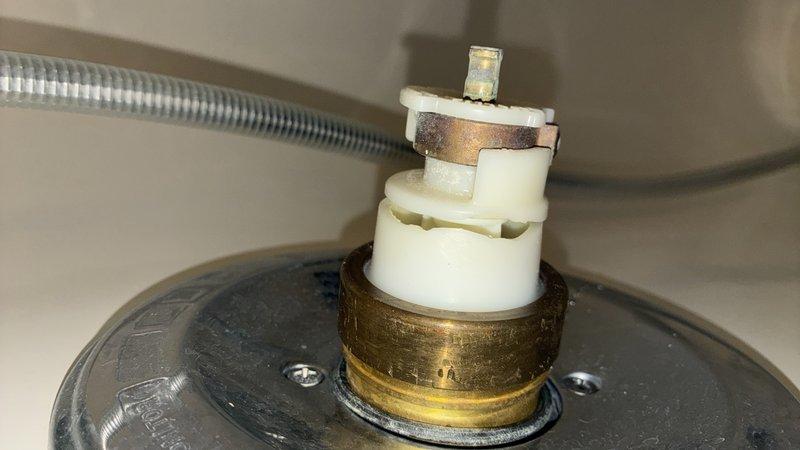 Responded to a leak complaint at a shower valve causing water intrusion through the floor to the garage below. Performed diagnostic inspection and removed the dual-stem shower cartridge assembly, which revealed significant corrosion and mineral deposits on the metal valve stems and brass threading. Documented the failed cartridge condition and provided rough estimate for cartridge replacement to resolve the active leak.