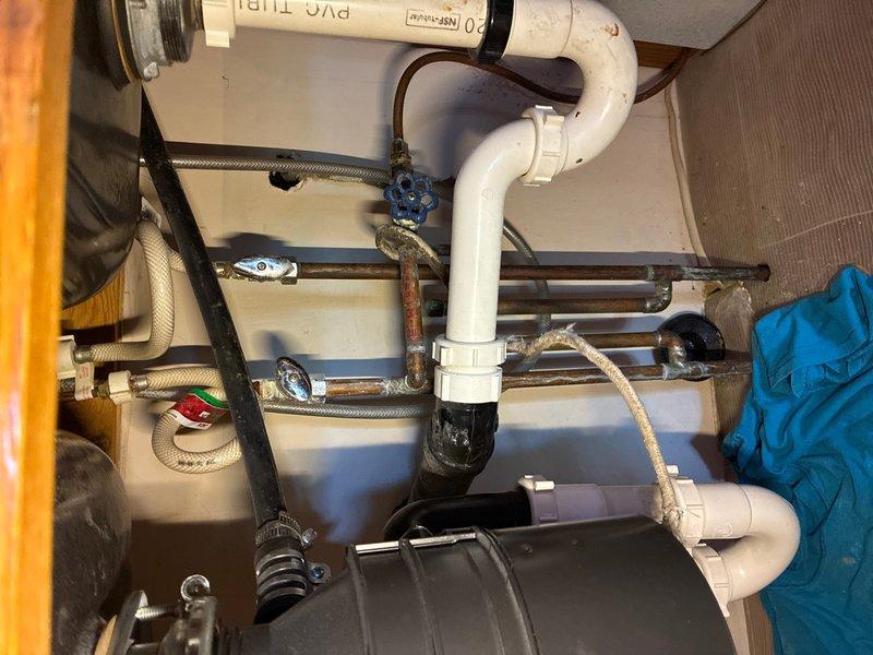 Responded to service call for garbage disposal replacement and leaking pipe investigation in a 40-year-old residence. Upon inspection of the under-sink plumbing system, assessed the existing garbage disposal unit and connected drainage piping for signs of failure and water intrusion. Identified compromised connections and aging drain lines exhibiting corrosion and deterioration at multiple junction points.

Removed the failed garbage disposal unit and disconnected associated drain fittings. Inspected the sink flange, mounting assembly, and discharge elbow for proper sealing and structural integrity. Evaluated the existing PVC drainage configuration, noting darkened areas around joints indicating previous moisture exposure and potential seal failure.

Installed new garbage disposal unit with fresh mounting hardware and properly torqued all connection points to manufacturer specifications. Replaced deteriorated drain fittings and tailpiece connections to ensure watertight seals throughou