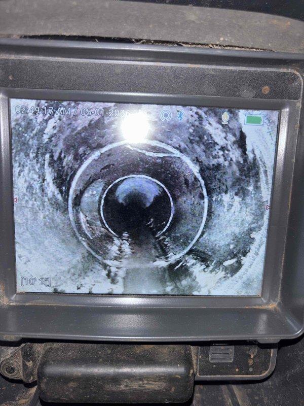 Performed video camera inspection of main sewer line to assess interior pipe condition. Inspection revealed significant scale buildup and residue accumulation on pipe walls throughout the line, with white and grayish deposits coating the interior surfaces. Documentation captured showing compromised flow capacity due to mineral deposits and debris accumulation within the system.