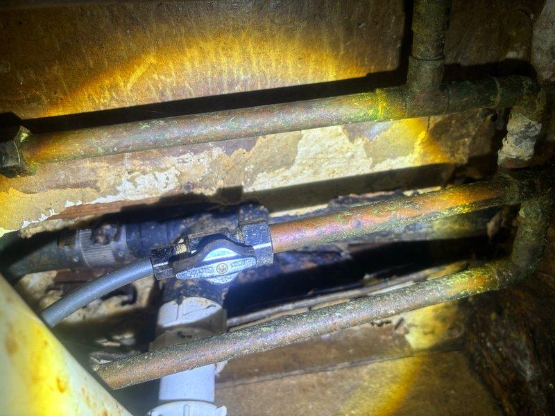 Responded to reported leaking faucet in kitchen. Upon inspection, identified worn supply line connections and deteriorated shut-off valve causing water seepage beneath sink. Accessed under-sink plumbing assembly featuring garbage disposal unit connected to PVC P-trap drainage system. Inspected brass tailpiece connections showing mineral buildup and corrosion contributing to leak issue. Tightened supply line fittings and assessed valve condition. Examined main water supply lines in mechanical space, noting aged copper piping with surface oxidation and compromised foam insulation, though structural integrity remained intact. Verified proper drainage flow through P-trap assembly and confirmed all connections secured with appropriate clamps. Leak successfully resolved and system restored to proper working condition.