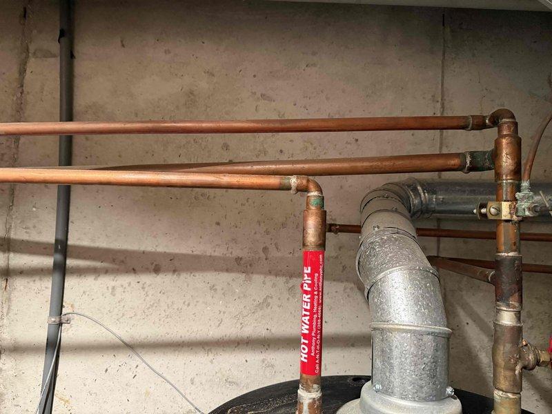 Conducted on-site assessment for 50-gallon water heater replacement in basement location. Evaluated existing water heater installation, including copper supply and discharge piping, shut-off valves, and venting system. Documented current plumbing infrastructure configuration with multiple copper pipe runs, fittings, and connections mounted to concrete block wall. Inspected condition of existing blue tank water heater unit and associated mechanical systems to provide accurate replacement estimate.