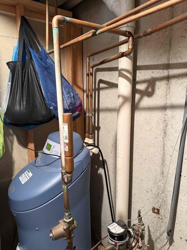 Conducted on-site assessment for 50-gallon water heater replacement in basement location. Evaluated existing water heater installation, including copper supply and discharge piping, shut-off valves, and venting system. Documented current plumbing infrastructure configuration with multiple copper pipe runs, fittings, and connections mounted to concrete block wall. Inspected condition of existing blue tank water heater unit and associated mechanical systems to provide accurate replacement estimate.