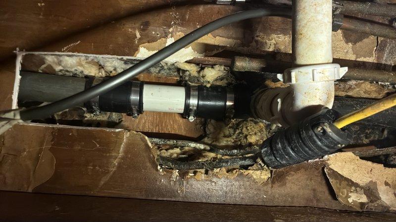 Responded to a kitchen drain line failure in the crawlspace area. Upon inspection, identified a deteriorated galvanized tee fitting showing significant corrosion and age-related degradation that required immediate replacement. Removed the failed galvanized tee section and repaired the drain line by installing a straight run of PVC pipe to restore proper drainage function. Work was completed in the underfloor area among existing plumbing infrastructure and wooden floor joists.