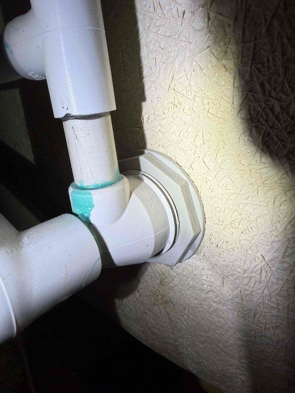 Responded to reported tub leak in basement area. Upon inspection, identified leaking drainage connections in white PVC plumbing assembly beneath tub. Evaluated P-trap configuration and associated drain piping for source of water intrusion. Noted corroded copper pipe in proximity to drainage system showing significant oxidation and deterioration. Tightened connections, secured pipes with proper clamps, and verified drainage system integrity. Documented plumbing configuration and condition of affected components. System tested and confirmed no active leaks at time of service completion.