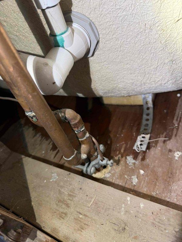 Responded to reported tub leak in basement area. Upon inspection, identified leaking drainage connections in white PVC plumbing assembly beneath tub. Evaluated P-trap configuration and associated drain piping for source of water intrusion. Noted corroded copper pipe in proximity to drainage system showing significant oxidation and deterioration. Tightened connections, secured pipes with proper clamps, and verified drainage system integrity. Documented plumbing configuration and condition of affected components. System tested and confirmed no active leaks at time of service completion.