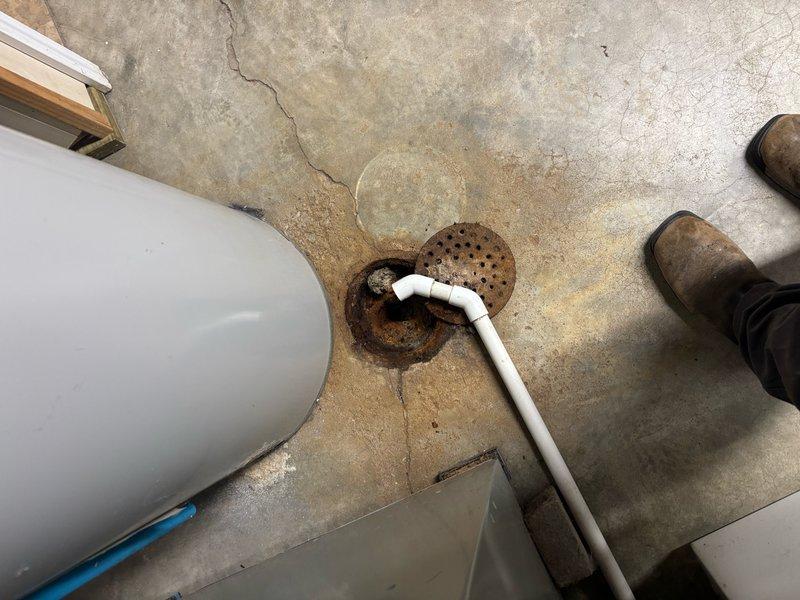 Responded to clogged drain issue at lowest level of property. Upon inspection, located floor drain in utility area near water heater showing signs of corrosion and restricted flow. Previous liner installation by another company was noted in service history. Accessed drainage system behind laundry appliances where multiple PVC supply and drain lines were present. Performed diagnostic assessment of drainage infrastructure, identifying blockage in floor drain assembly. Cleared obstruction and restored proper drainage function. Verified water flow through system and confirmed resolution of reported clogging issue.