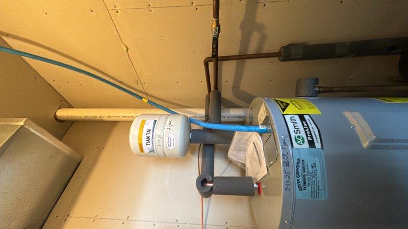 Completed comprehensive whole-home plumbing inspection per customer request from promotional campaign. Thoroughly evaluated water heater installation in utility closet, including copper supply lines, blue corrugated discharge piping, and associated components such as expansion tank or filtration system mounted to overhead plumbing. Inspected WOODFORD brand pressure regulator valve assembly installed in recessed wall box with accompanying pressure gauge to verify proper system pressure regulation and monitoring capability. Documented all findings with photographic evidence for customer records.