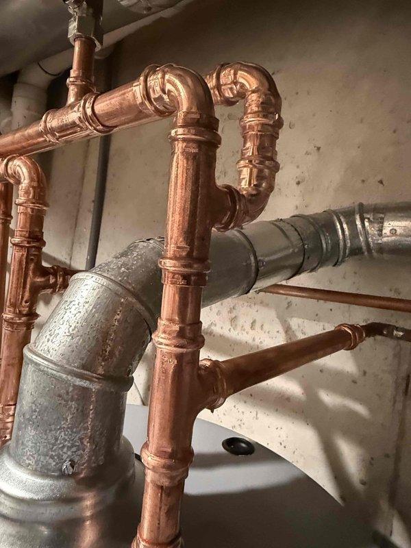 Completed installation of a 50-gallon gas-fired water heater with thermal expansion tank in residential utility space. All copper supply and discharge piping was configured to manufacturer specifications with proper shutoff valves and compression fittings. The thermal expansion tank was installed on the cold water supply line to protect against thermal expansion in the closed plumbing system. All connections were pressure-tested and verified for proper operation before completing the installation.