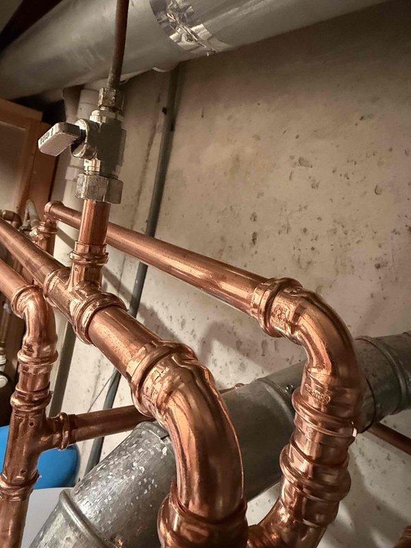 Completed installation of a 50-gallon gas-fired water heater with thermal expansion tank in residential utility space. All copper supply and discharge piping was configured to manufacturer specifications with proper shutoff valves and compression fittings. The thermal expansion tank was installed on the cold water supply line to protect against thermal expansion in the closed plumbing system. All connections were pressure-tested and verified for proper operation before completing the installation.