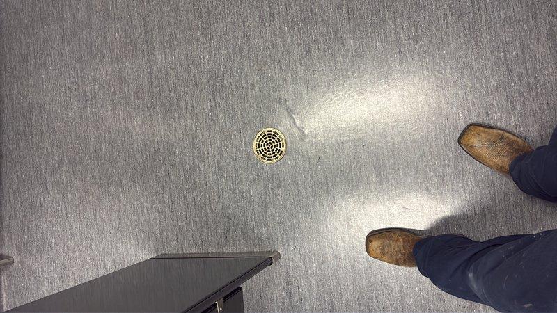 Conducted site assessment of commercial men's bathroom experiencing recurring flooding issues affecting adjacent office space. Inspected existing floor drain system and documented current drain elevation relative to bathroom fixtures and floor level. Provided estimate for drain relocation and lowering to prevent water overflow and protect office areas from future flooding events.