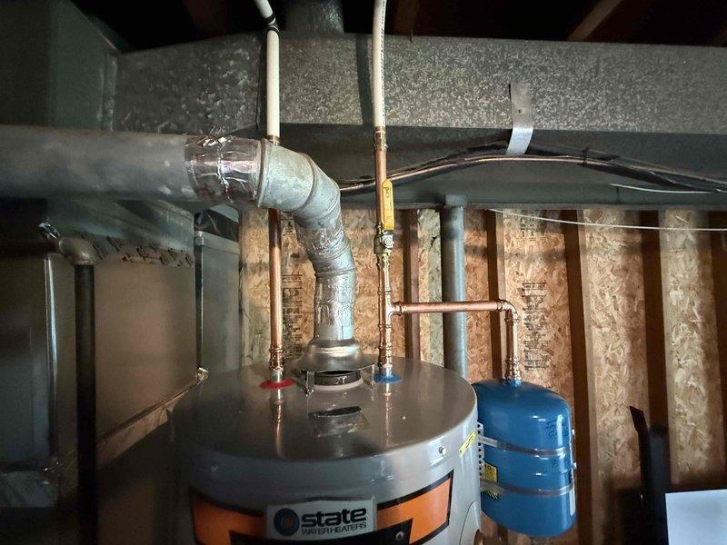 Installed a 40-gallon State brand gas water heater in commercial utility space, replacing existing unit. Connected incoming cold water supply and outgoing hot water distribution lines using copper piping with brass fittings and shutoff valves. Installed blue thermal expansion tank to protect system from pressure buildup due to thermal expansion. Secured all gas connections, verified proper venting through existing ductwork, and ensured compliance with commercial plumbing codes. Tested system operation, confirmed proper ignition, and verified no leaks at all connection points.