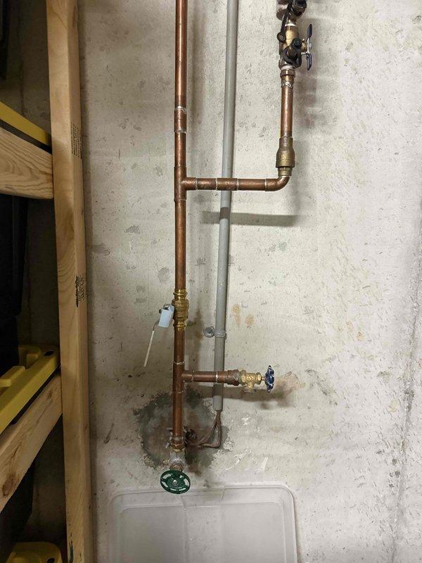 Responded to report of faulty main water shut off valve that was leaking and failing to properly shut off water supply. Upon inspection, found the existing gate valve with green wheel handle had deteriorated internal components causing both the leak and inability to achieve full closure. Replaced the defective main shut off valve with new brass ball valve assembly, utilizing proper copper pipe connections and fittings. Installed catch pan beneath valve assembly to protect against future leaks. Tested new valve installation for proper operation, confirming complete water shut off capability and verified no leaks at connections. System restored to full working order with reliable main water shut off control.