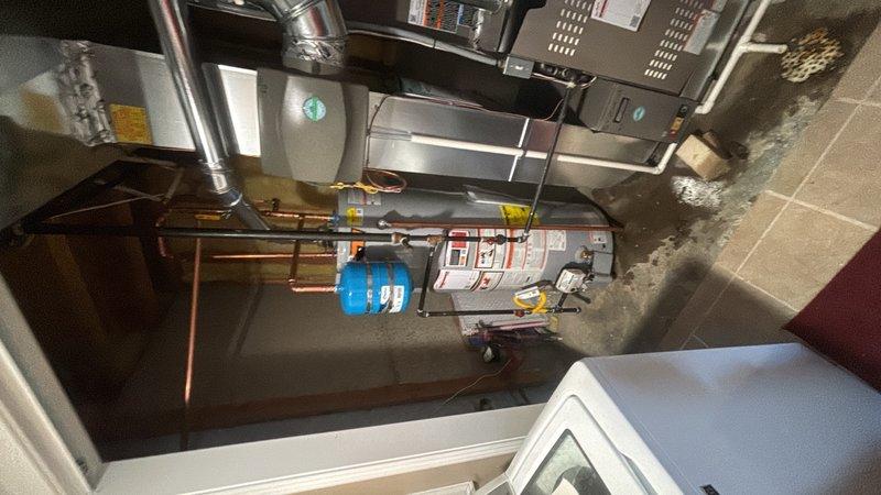 Completed installation of a 50-gallon gas water heater in mechanical room, which required relocating washer and dryer to access the work area. Removed existing unstable water heater that had been improperly supported with bricks underneath. Installed new unit with proper connections including PEX supply lines, 3/4" pressure relief valve (PRV), and 1/4 turn valve for humidifier connection. All plumbing connections were secured with brass fittings, temperature and pressure relief valve assembly was properly installed and tested, and unit was commissioned to verify proper operation and safety compliance.