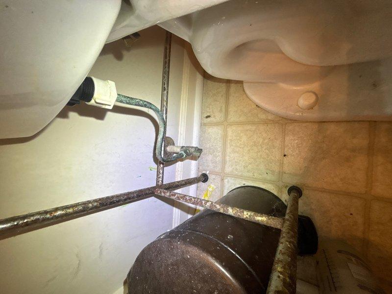 Completed plumbing maintenance inspection in mechanical room and restroom facility. Assessed HVAC-adjacent plumbing systems and documented toilet supply line connections, noting age-related mineral deposits and surface oxidation on shut-off valve and supply piping requiring monitoring for potential future replacement.
