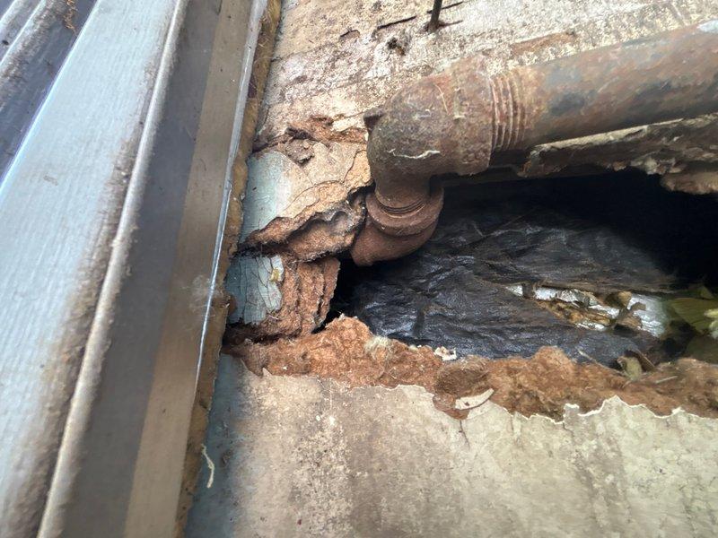 Responded to service call for gas line removal and capping running from basement to garage. Upon inspection, found severely corroded gas piping with extensive rust deterioration throughout the line, indicating prolonged exposure to moisture and age-related degradation. The existing pipe exhibited compromised structural integrity with heavy oxidation layers covering the metal surfaces. Successfully capped the gas line at the point of origin to ensure safe termination of gas supply. Removed the deteriorated gas piping section that ran through the crawl space and into the garage area near the overhead door mechanism. Verified proper cap installation and conducted pressure testing to confirm complete gas line isolation and system safety. Documented existing conditions showing water damage to surrounding building materials and insulation in the affected area.