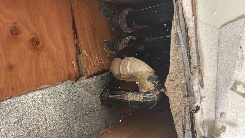 Responded to a water leak originating from the upper unit (Apt 8) affecting the lower unit (Apt 4). Conducted visual inspection and documentation of affected plumbing areas, revealing deteriorated pipe insulation and exposed piping components at wall and floor junctions. Observed compromised foam pipe insulation that has cracked, separated, and lost structural integrity, along with exposed metal pipes, fittings, and mounting hardware in corner cavity areas where wooden flooring meets wall paneling. Documented conditions showing evidence of moisture intrusion and age-related degradation to insulation materials surrounding plumbing infrastructure. Prepared photographic documentation and estimate for necessary repairs to address leak source and restore proper pipe insulation and protection.