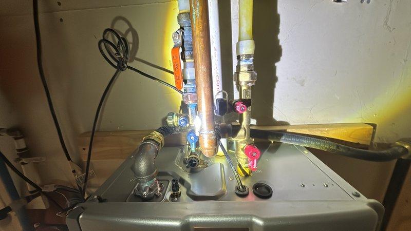 Completed scheduled plumbing maintenance visit including tankless water heater system flush and inspection. Serviced gas water heater installation with multiple shut-off valves, verified proper operation of pressure relief valve assembly, and inspected copper piping, PEX tubing, and gas line connections throughout the system. Performed maintenance on ceiling-mounted plumbing fixtures and verified all connections and mounting hardware were secure.